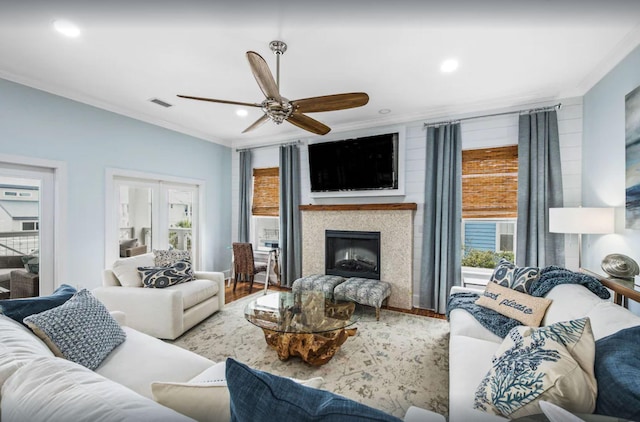 living room featuring ceiling fan, visible vents, wood finished floors, and crown molding