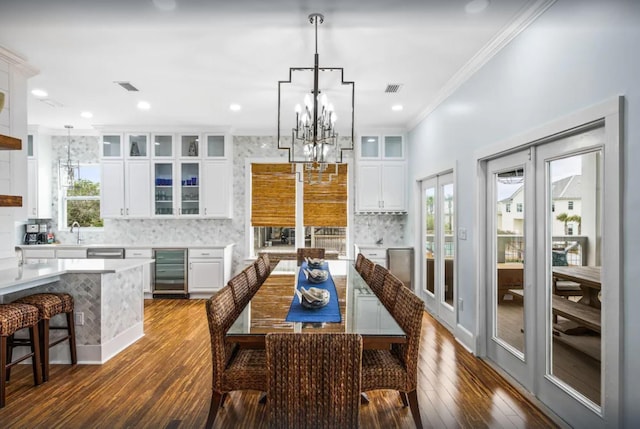 dining space with visible vents, wine cooler, an inviting chandelier, and ornamental molding