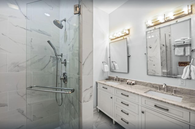 bathroom with a marble finish shower, marble finish floor, double vanity, and a sink