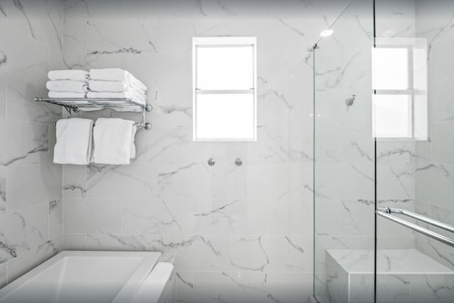 bathroom featuring plenty of natural light and a marble finish shower