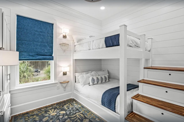 bedroom featuring wooden walls and baseboards