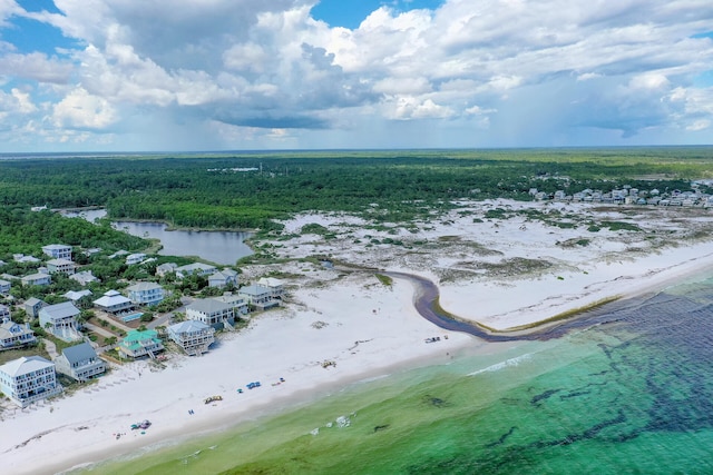 drone / aerial view featuring a wooded view, a beach view, and a water view