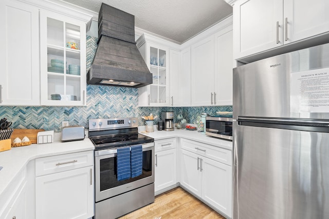 kitchen featuring backsplash, premium range hood, light countertops, white cabinets, and stainless steel appliances