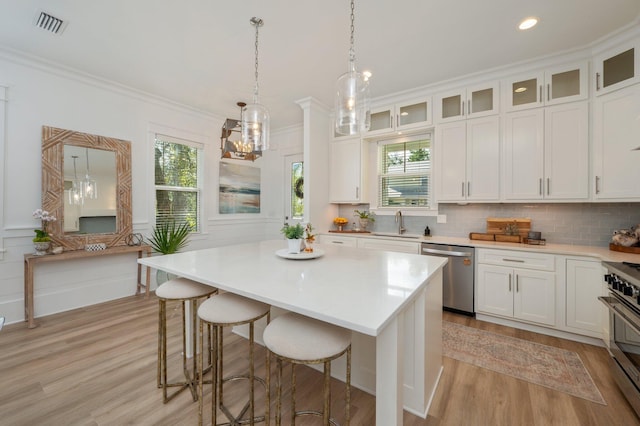 kitchen with stainless steel appliances, tasteful backsplash, crown molding, and white cabinetry