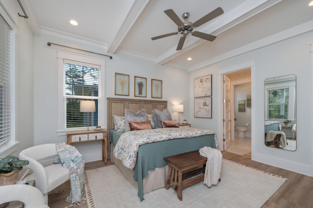 bedroom with beam ceiling, multiple windows, light wood finished floors, and ensuite bathroom