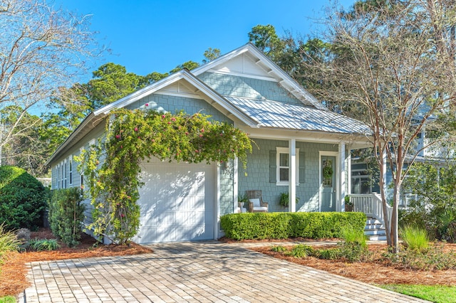 view of front of home featuring decorative driveway, covered porch, and an attached garage