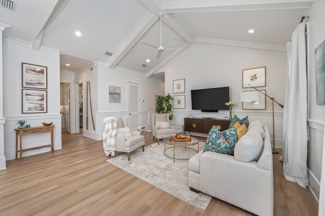 living area with light wood-type flooring, visible vents, vaulted ceiling with beams, and wainscoting