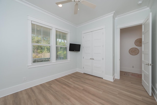 unfurnished bedroom with light wood-type flooring, ornamental molding, a closet, baseboards, and ceiling fan