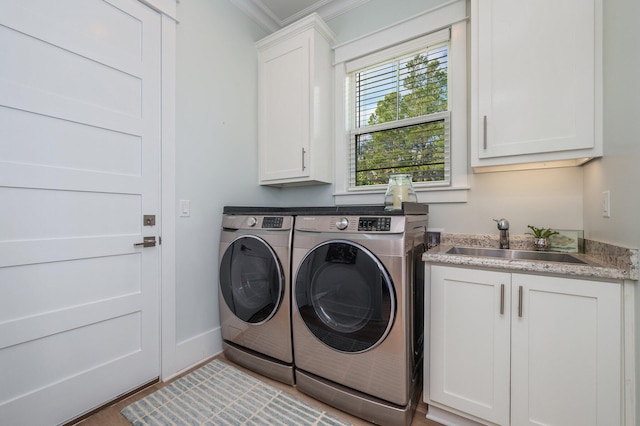 washroom with independent washer and dryer, ornamental molding, a sink, cabinet space, and baseboards