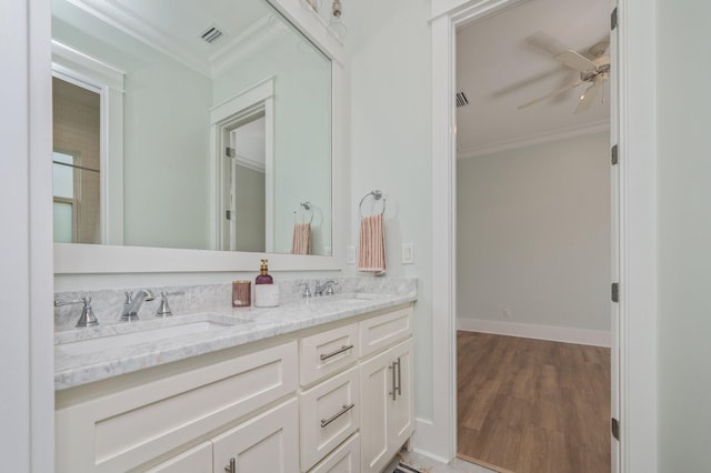 bathroom with visible vents, ornamental molding, a ceiling fan, a sink, and wood finished floors