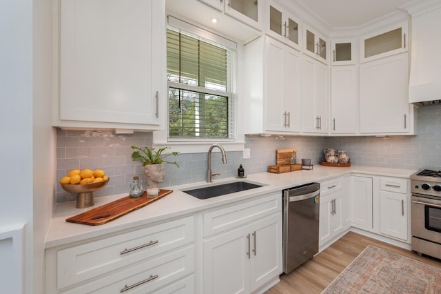 kitchen with a sink, stainless steel appliances, light wood-style floors, white cabinets, and light countertops