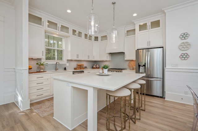 kitchen featuring a breakfast bar area, a sink, light countertops, appliances with stainless steel finishes, and a center island