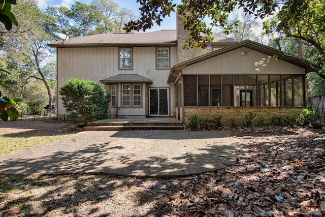 view of front of home with fence, brick siding, a sunroom, and a chimney