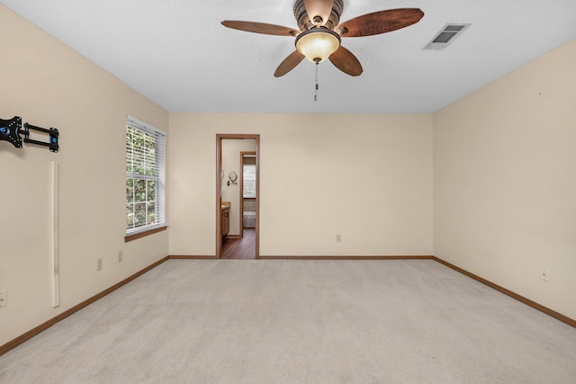 empty room featuring light carpet, visible vents, and baseboards