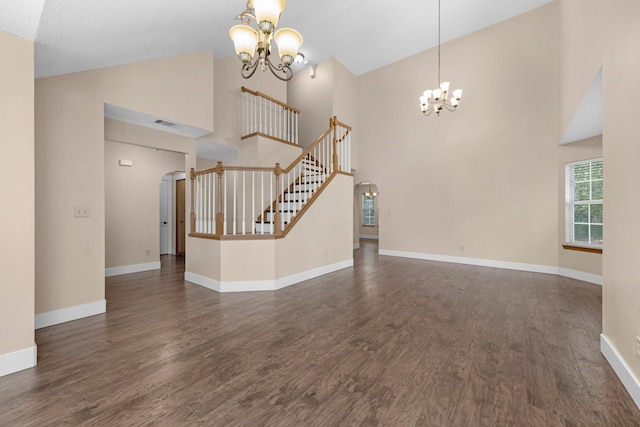 unfurnished living room featuring a notable chandelier, wood finished floors, arched walkways, and baseboards