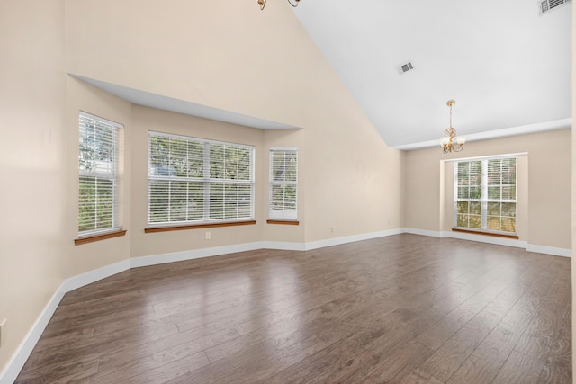 empty room featuring visible vents, dark wood-type flooring, high vaulted ceiling, baseboards, and a chandelier