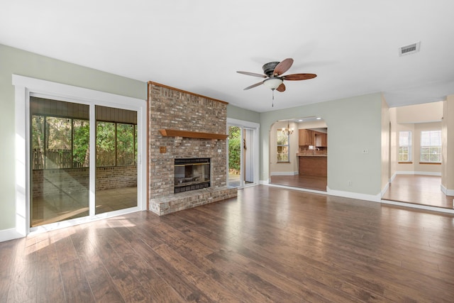 unfurnished living room featuring visible vents, ceiling fan with notable chandelier, plenty of natural light, and wood finished floors