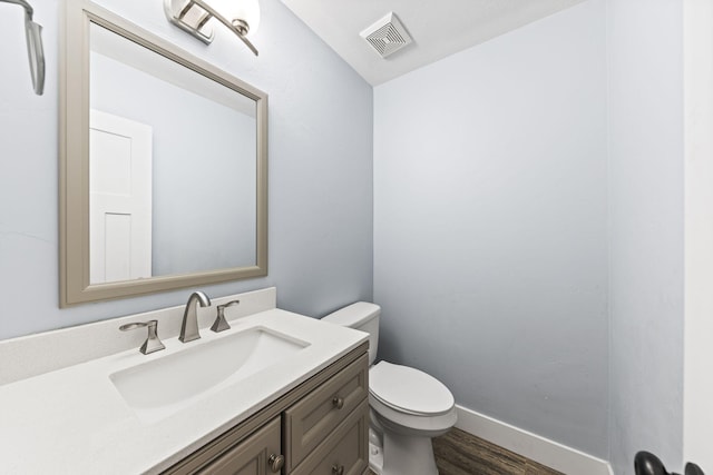 bathroom featuring visible vents, toilet, wood finished floors, baseboards, and vanity