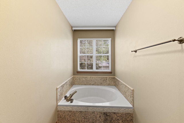 bathroom featuring a garden tub and a textured ceiling