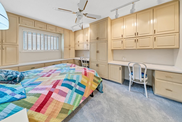 bedroom with built in desk, light colored carpet, and a ceiling fan