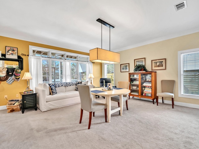 dining room with light carpet, a healthy amount of sunlight, visible vents, and ornamental molding