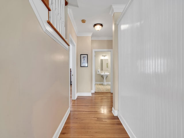 hall with light wood-style floors, baseboards, and ornamental molding