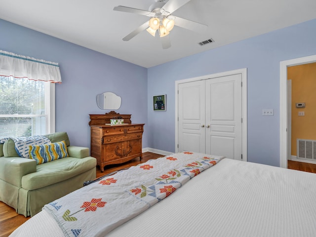 bedroom with visible vents, baseboards, a closet, and wood finished floors