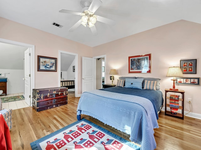 bedroom with a ceiling fan, wood finished floors, visible vents, baseboards, and vaulted ceiling