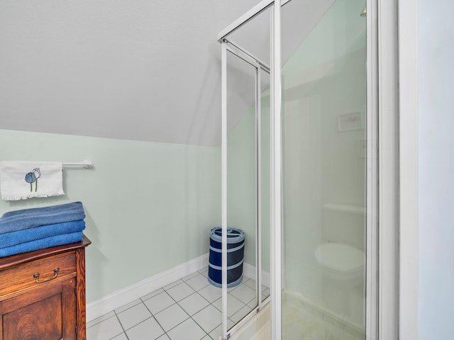 bathroom featuring tile patterned flooring, a shower stall, baseboards, and vaulted ceiling