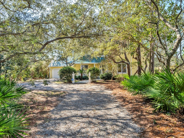 obstructed view of property featuring a garage, metal roof, and driveway