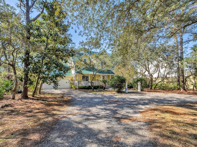 view of front of home with gravel driveway, an attached garage, and metal roof