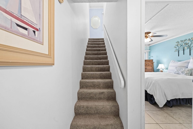 stairs with tile patterned flooring, crown molding, a ceiling fan, and a textured ceiling