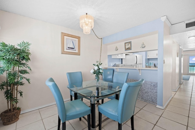 dining space featuring visible vents, a textured ceiling, light tile patterned floors, baseboards, and a chandelier