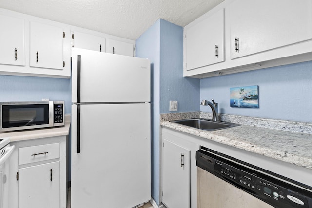 kitchen with a sink, a textured ceiling, appliances with stainless steel finishes, white cabinets, and light countertops