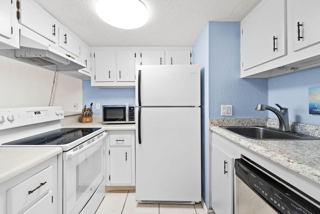 kitchen with light countertops, appliances with stainless steel finishes, light tile patterned flooring, a textured ceiling, and a sink