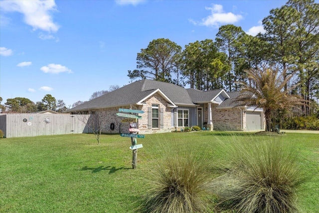 view of front facade with brick siding, a front yard, fence, and a garage