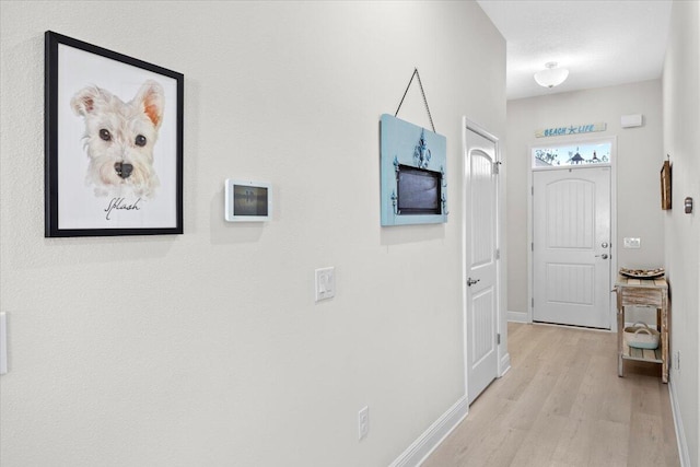 hall with baseboards and light wood-type flooring