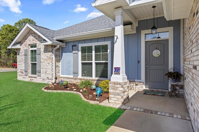 property entrance featuring stone siding, a yard, roof with shingles, board and batten siding, and brick siding