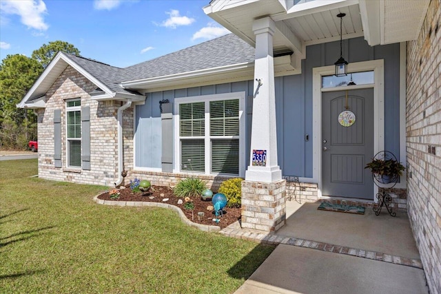 entrance to property with roof with shingles, stone siding, board and batten siding, a lawn, and brick siding