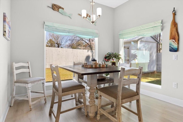 dining room with baseboards, light wood-style floors, and an inviting chandelier