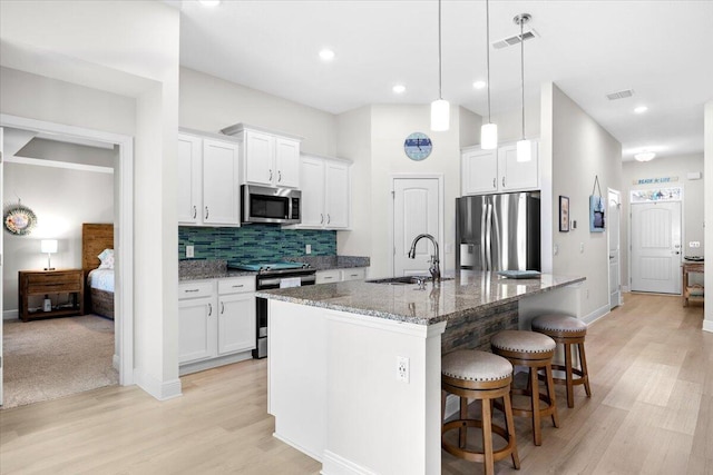 kitchen featuring tasteful backsplash, visible vents, a breakfast bar area, stainless steel appliances, and a sink