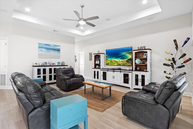 living area featuring light wood-type flooring, a tray ceiling, baseboards, and recessed lighting