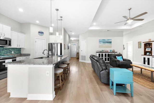 kitchen featuring a breakfast bar, decorative backsplash, stone countertops, stainless steel appliances, and a sink