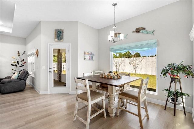 dining area with light wood-type flooring, baseboards, and a notable chandelier