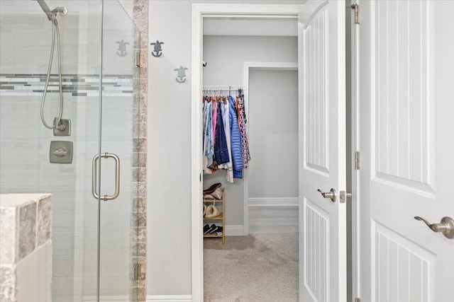 full bathroom featuring a spacious closet, a shower stall, and baseboards