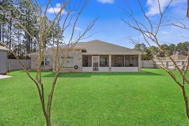 back of house with a fenced backyard, a lawn, brick siding, and a sunroom