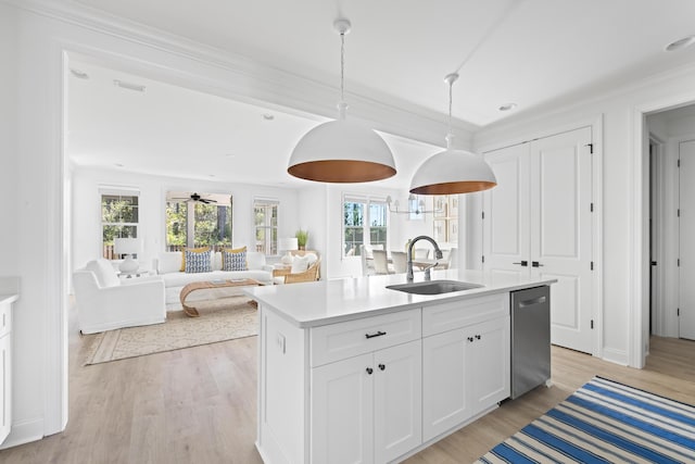 kitchen with light wood-type flooring, a kitchen island with sink, a sink, stainless steel dishwasher, and light countertops