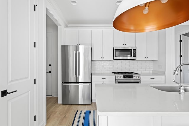 kitchen featuring light countertops, white cabinets, appliances with stainless steel finishes, and a sink