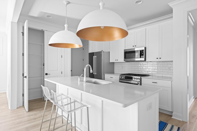 kitchen featuring a center island with sink, light wood-style flooring, appliances with stainless steel finishes, white cabinets, and a sink