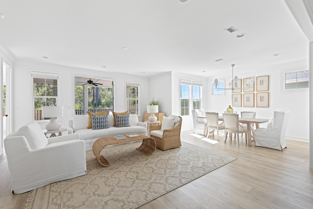 living room featuring light wood finished floors, visible vents, crown molding, and a wealth of natural light